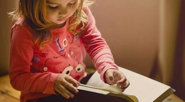 Young girl turnign a page of a book