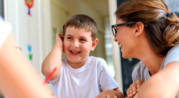 Young boy with hand up to his ear with adults.