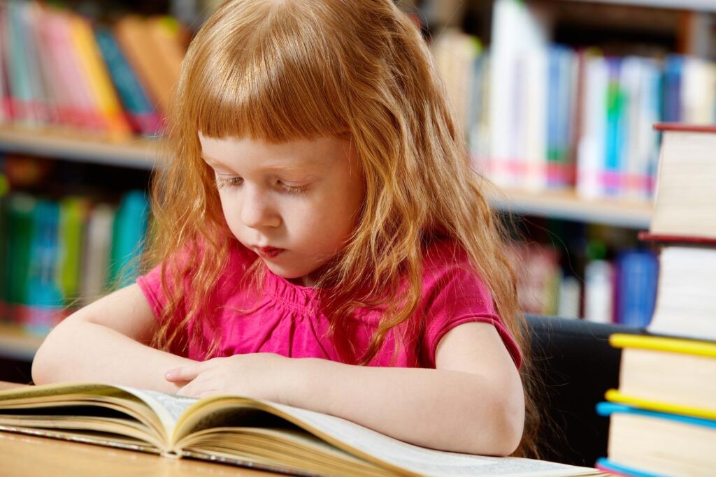 Young red headed girl reading