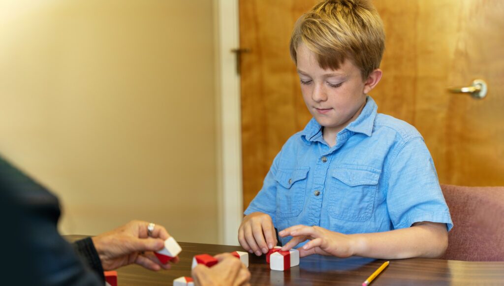 Young boy arranging blocks as part of a psycheducational evaluation