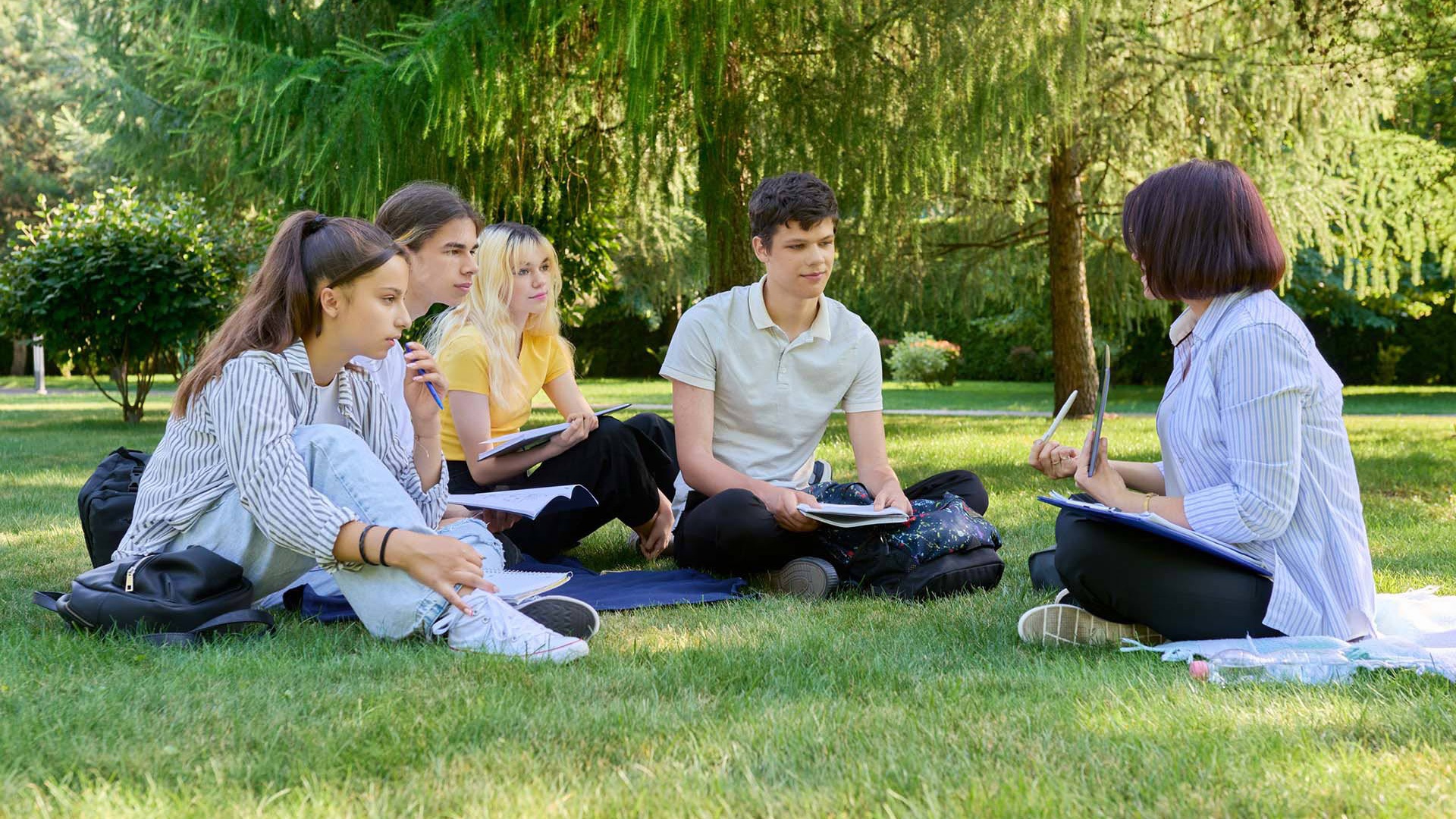 Group of young adults sitting in the grass with an instructor