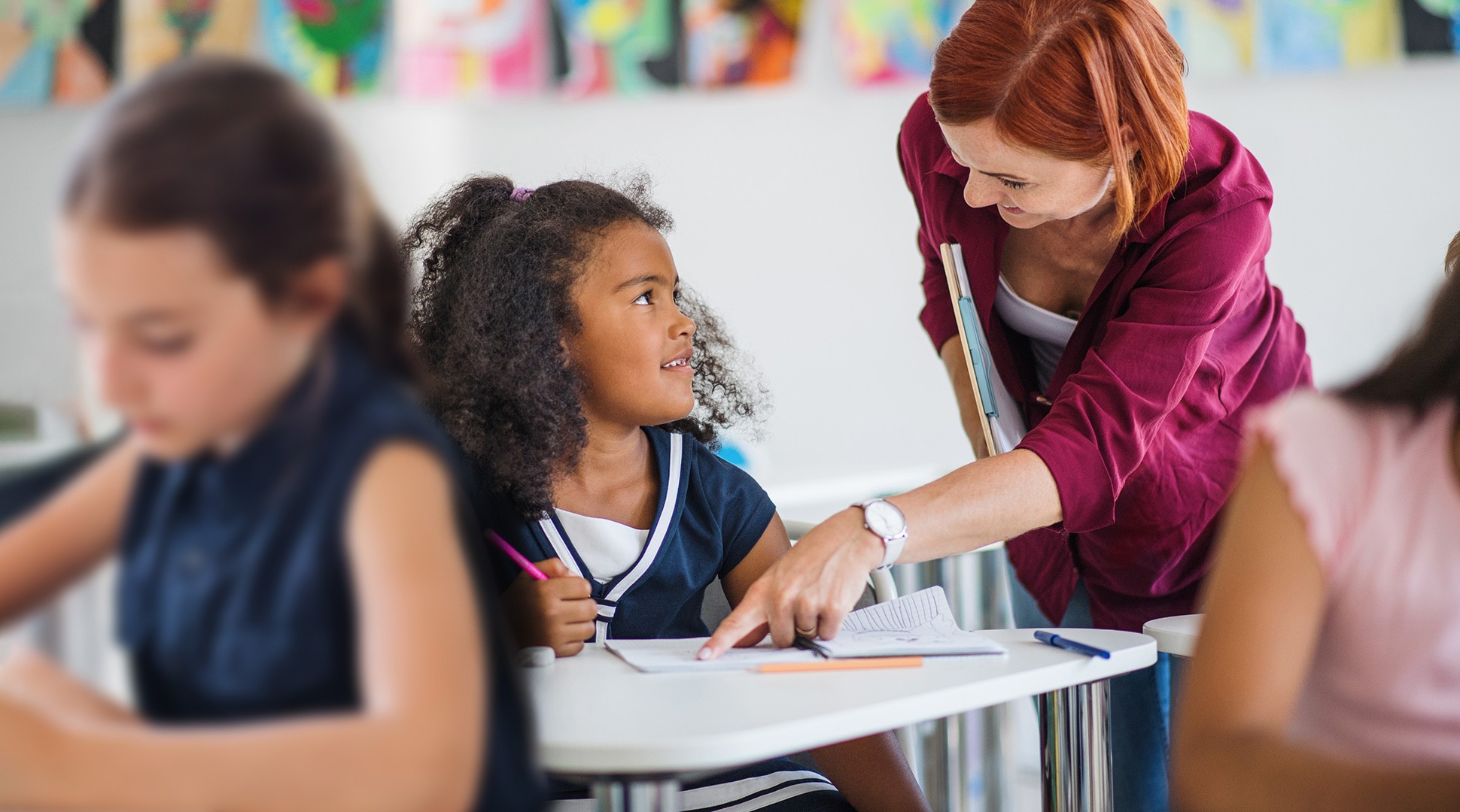 Teacher works with a student in a classroom.
