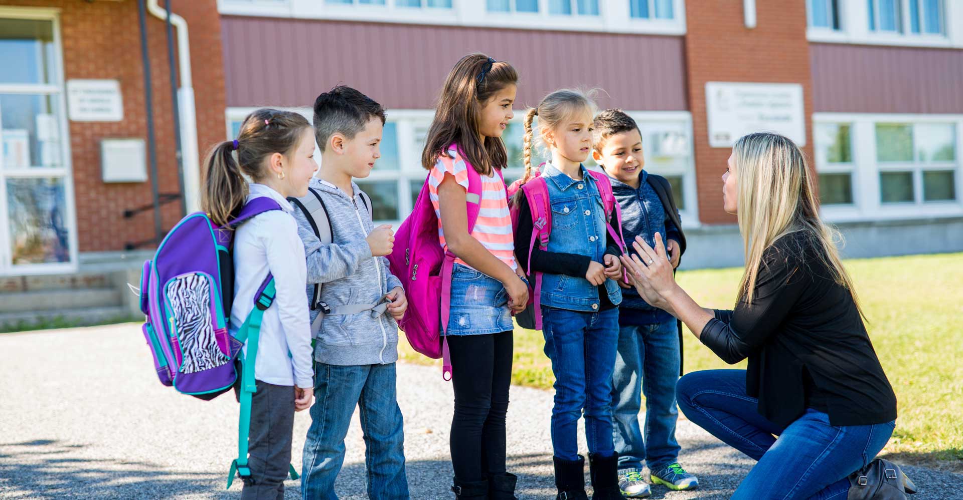 teacher kneeling down with group of kids