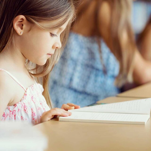 An elementary student reads a book in class.