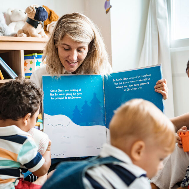 A teacher reads a large picture book to toddlers in an early childcare center.
