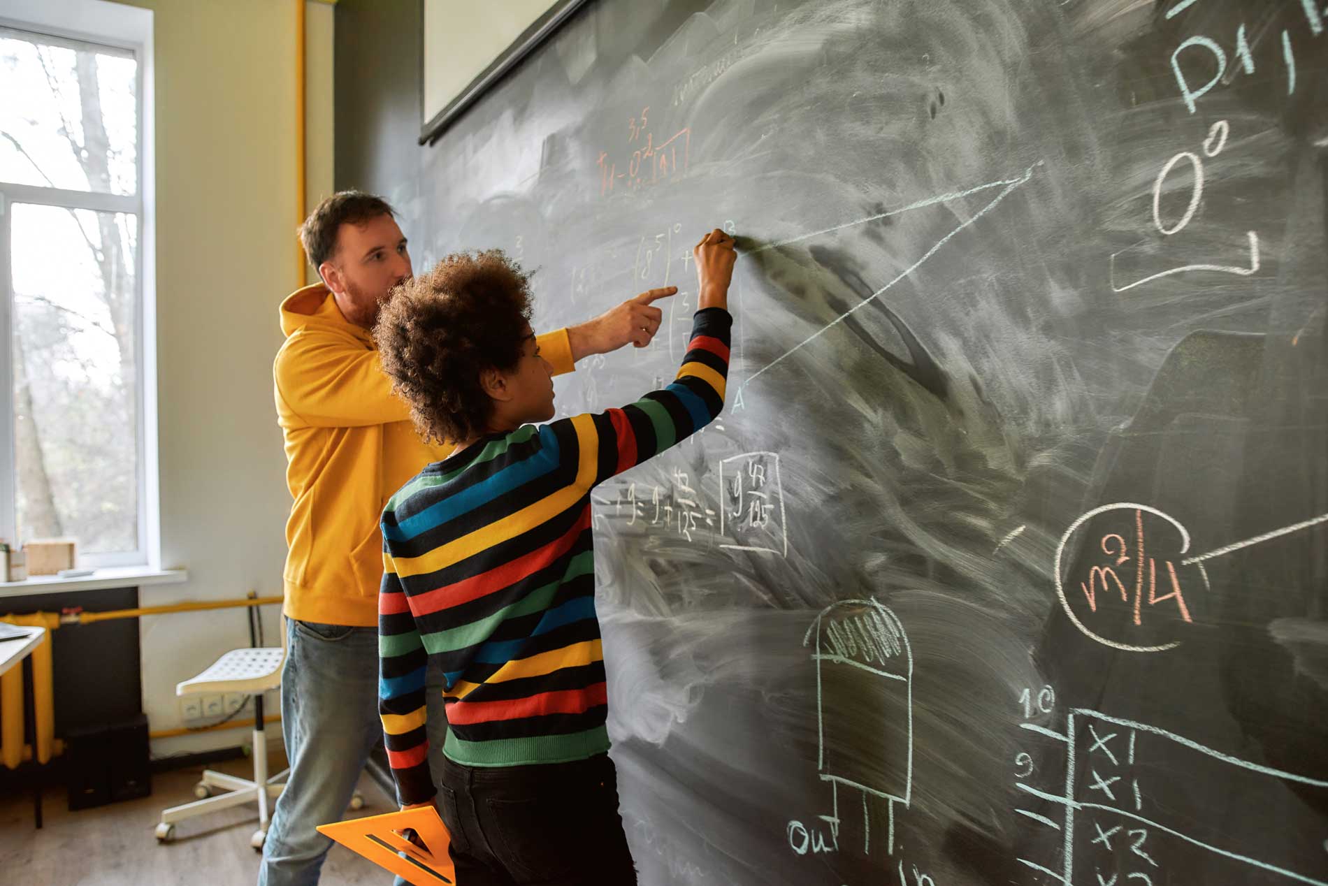 male math student at chalkboard with teacher