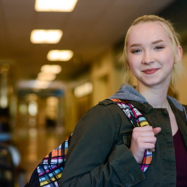 Young female student smiles in a school hallway