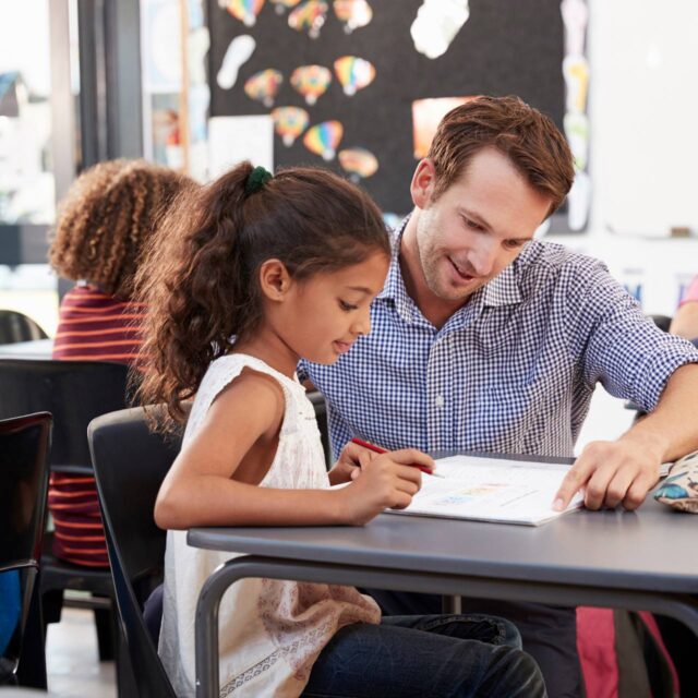 Male teacher helping a young girl student