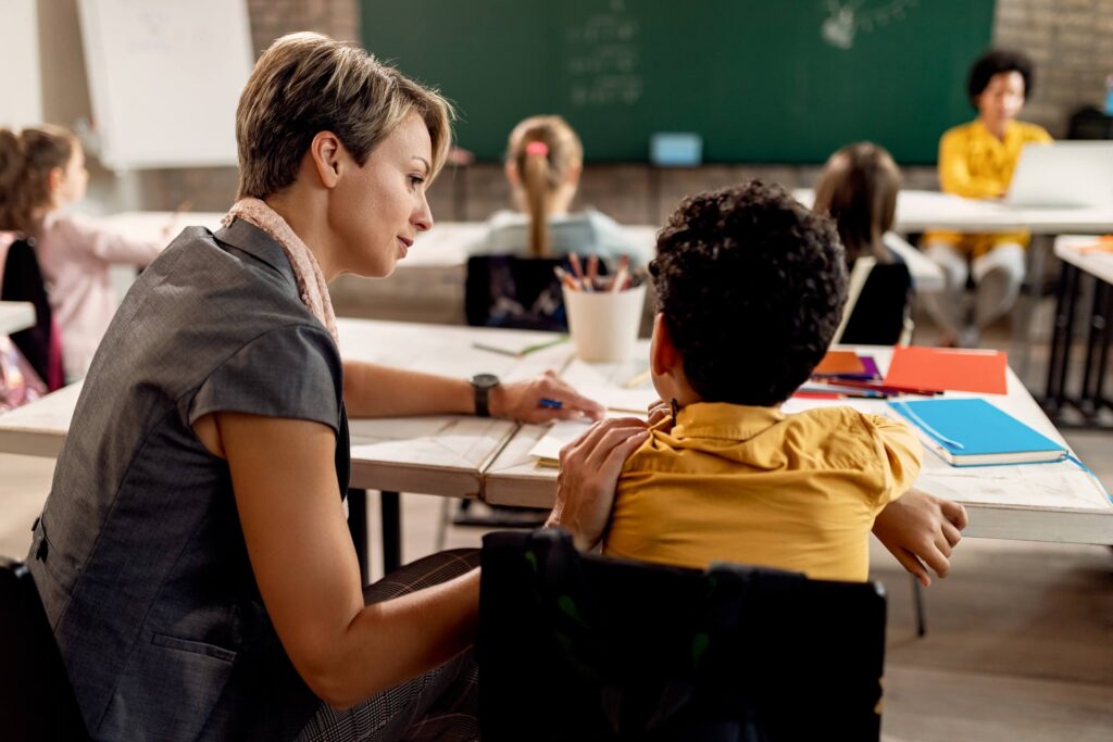 Teacher with boy student in classroom.