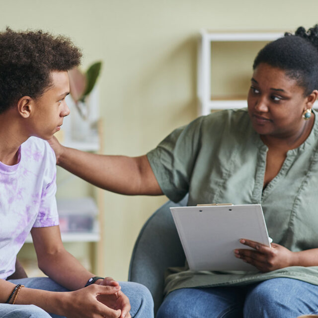 A therapist supports a high school student in a group session.