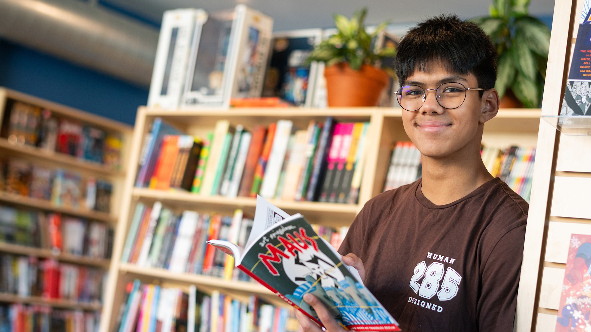 High school student reading Maus in a library.