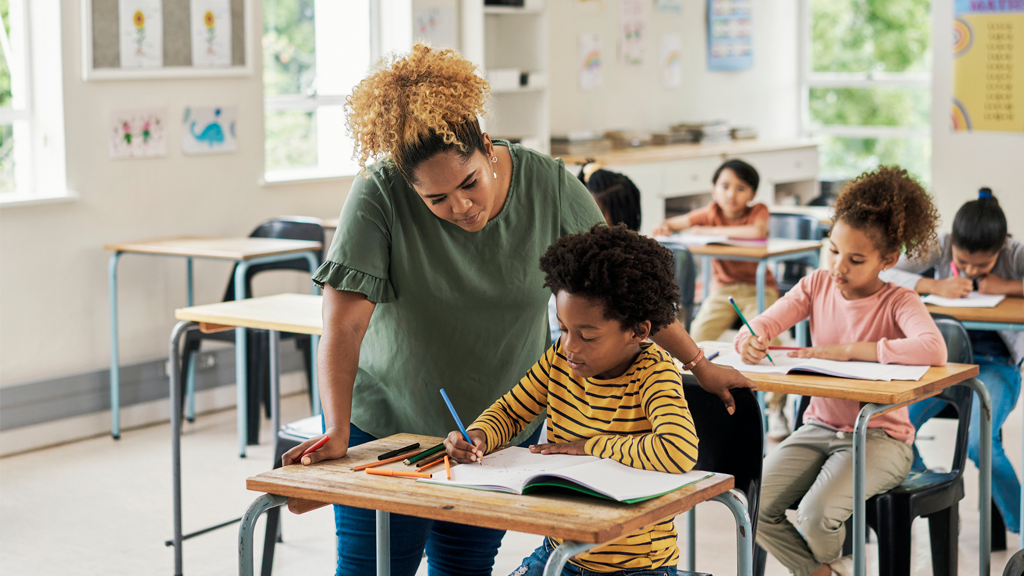 Teacher in classroom helping student